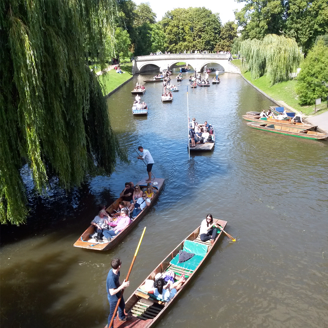 Punts sailing under and around Claire College Bridge in Cambridge.